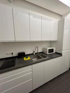 a kitchen with white cabinets and a sink and a microwave at 29qm großes Zimmer im Elbvorort in Hamburg