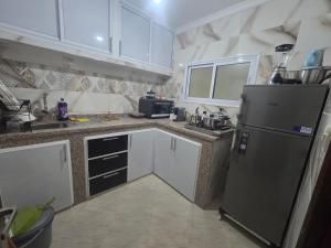 a kitchen with a stainless steel refrigerator and white cabinets at Appartement Laayoune in Laayoune +15 photos