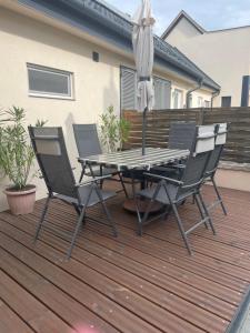 a table and chairs on a deck with an umbrella at Pupi Apartmanház in Balatonlelle