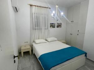 a small white bedroom with a bed and a chandelier at Villa Joseph in Agia Fotia