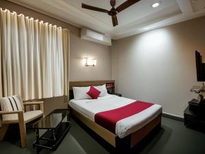 坦贾武尔Naadi Hotel New Busstand Thanjavur的一间卧室，里面有一张床、一把椅子和一张桌子