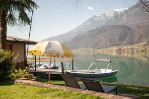 a boat on the water with two chairs and an umbrella at Leuchtenburg am See in Caldaro