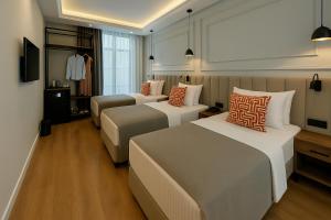a hotel room with three beds and a tv at Center Port Hotel Karaköy in Istanbul