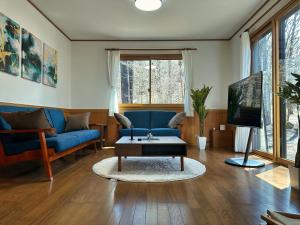 a living room with a blue couch and a coffee table at Noël Kitakaruizawa Seiryu-2 Riverside retreat in Tsumagoi