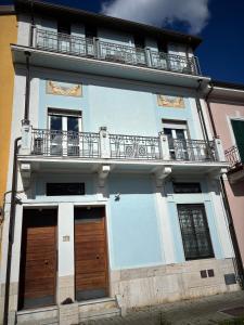Edificio blanco con puertas de madera y balcón en - Seaside Nest-Free Parking & Beach, en Marina di Carrara