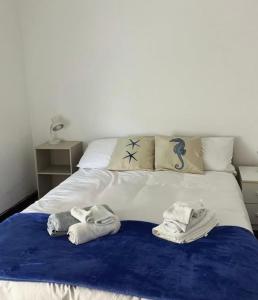 twee handdoeken op een bed met een blauwe deken bij La melanetta in Noli