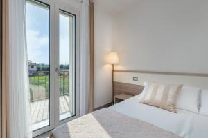 sypialnia z łóżkiem i dużym oknem w obiekcie Appartamenti Villa Campo Rosso w mieście Colà di Lazise +37 zdjęć