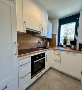 a kitchen with white cabinets and a sink and a window at 7034 Enseling in Dahme +16 photos