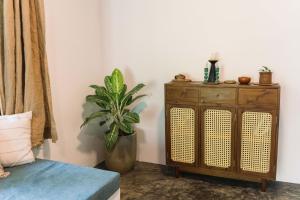 a room with a plant and a wooden cabinet at Podi Beach House Mawella in Tangalle