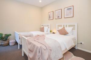 2 camas en un dormitorio con sábanas y almohadas blancas en Luxury Townhouse Stay, en Melbourne
