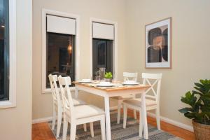 Un comedor con una mesa y sillas blancas. en Luxury Townhouse Stay, en Melbourne
