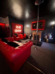 a living room with a red couch and a tv at Play Queen - A Playful Unique Hot Tub Retreat in Sedgley +22 photos