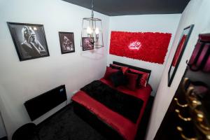 a bedroom with a bed with red pillows and a tv at Play Queen - A Playful Unique Hot Tub Retreat in Sedgley
