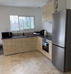 eine Küche mit Edelstahlkühlschrank und Schränken in der Unterkunft 3 chambres à côté de sarlat, dans le Périgord ! in Carsac-Aillac