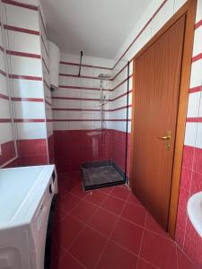 a red tiled bathroom with a shower and a door at Beachfront Apartament in Golem in Golem +13 photos