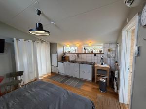 a small kitchen with white cabinets and a bed in a room at Eget boende i privat uthuslänga in Alingsås