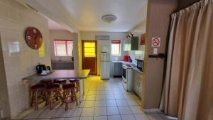 a kitchen with a counter and stools in it at ANASTASIS, SEABREEZE CABANAS in George