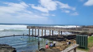 a group of people standing in the water near a pier at ANASTASIS, SEABREEZE CABANAS in George