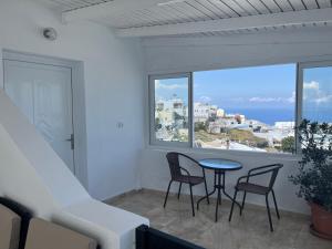 uma varanda com uma mesa e cadeiras e uma janela em Stella Nomikou Apartments em Firostefani