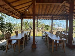 a group of wooden tables and chairs under a pavilion at Parlezo Cottage Dintor in Ntuar