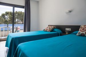 two beds in a room with a view of the ocean at RVHotels Apartamentos Treumal Park in Platja d'Aro