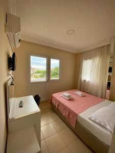 a bedroom with a bed and a desk and a window at Mandarin Beach Hotel in Gumuldur