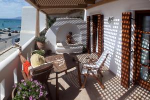 a woman sitting on a balcony with a table and chairs at Enosis apartments in Agia Anna , Apartment Argo in Agia Anna Naxos