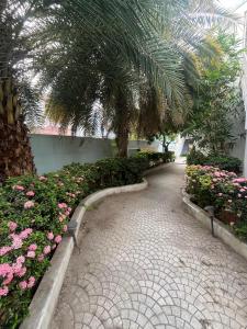 einen Gehweg in einem Garten mit Blumen und einer Palme in der Unterkunft Sakthi Guest House in Tiruvannāmalai