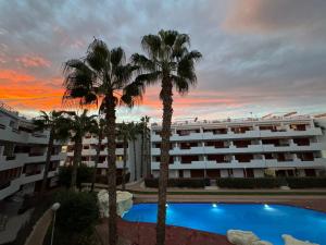 a hotel with palm trees in front of a building at El Rincon in Alicante