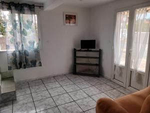 a living room with a tv and two windows at Maison au Bois-Court in Le Tampon +5 photos