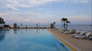 a swimming pool next to the ocean with lounge chairs at Coastal getaway at Cha-am in Ban Bang Sai Yoi (1)