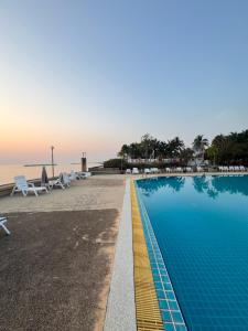 a swimming pool next to a beach with chairs and the ocean at Coastal getaway at Cha-am in Ban Bang Sai Yoi (1)