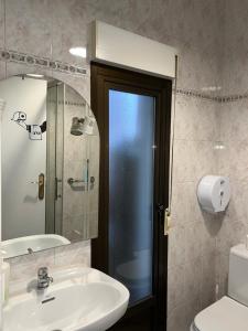 Un baño con lavabo, inodoro y espejo. en Roomin Hostel, en Salamanca