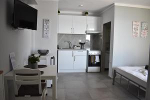 a small kitchen with white cabinets and a table and a bed at Fotini's studio in Paleo Tsifliki