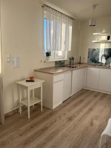 a kitchen with white cabinets and a table and a window at Apartament Lazurowy in Puck