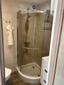 a shower with a glass door in a bathroom at Apartament Lazurowy in Puck