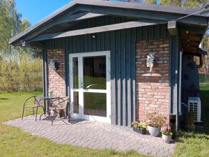 a small house with a table and chairs on a patio at Domek Leśny Zakątek z klimatyzacją in Bartel Wielki +16 photos