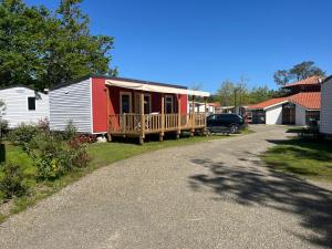 una casita roja y blanca con porche en Mobile Home 6 personnes, en Seignosse 5 fotos más