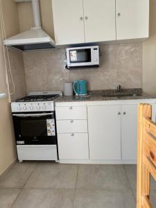 a kitchen with a stove and a microwave at Departamentos Belgrano in San Luis
