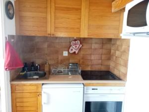 a kitchen with wooden cabinets and a sink at Cozy studio à coté du lac in Jausiers +1 photo