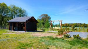 a small shed with a playground in a field at Malinówka Kruczy Borek in Kruczy Borek