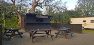 a group of picnic tables in front of a black shack at Cosy family friendly static in Pistyll +8 photos