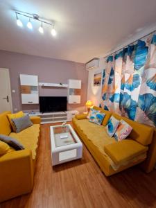 a living room with a yellow couch and a tv at Apartment Lidija in Krk