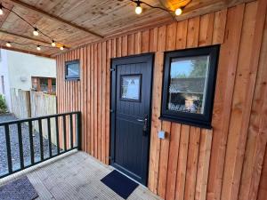 a house with a black door on a wooden wall at Tigh-Na-Mara Hotel in Sandhead