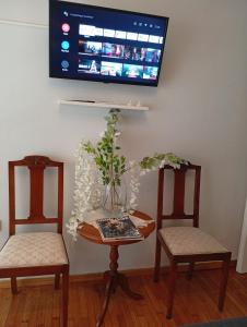2 Stühle und ein Tisch mit einem TV an der Wand in der Unterkunft Smart cozy apartment in Athens! in Athen