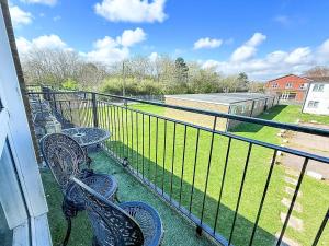 a balcony with two chairs and a fence at Superb Chalet, Sleeps 8, Nearby Hemsby Beach In Norfolk Ref 18193B in Hemsby