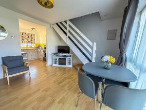 a living room with a table and chairs and a staircase at Superb Chalet, Sleeps 8, Nearby Hemsby Beach In Norfolk Ref 18193B in Hemsby +11 photos