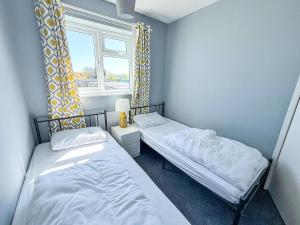 two beds in a small room with a window at Superb Chalet, Sleeps 8, Nearby Hemsby Beach In Norfolk Ref 18193B in Hemsby