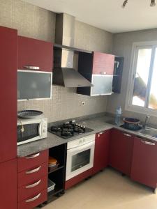 a kitchen with red cabinets and a stove top oven at Ecrin Moderne Islan a Agadir in Agadir