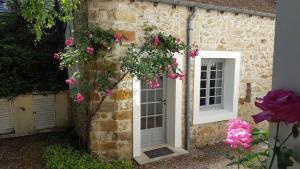 a stone house with a white door and pink flowers at Tiny House classée in Maincy